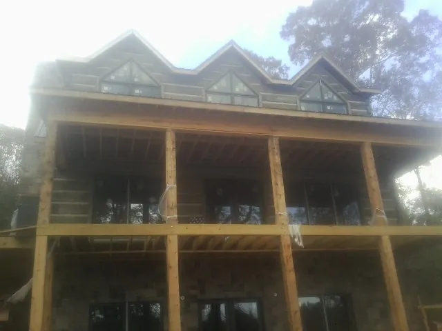 Dormers and porch framing on a large log home under construction — Roof Coating work by our crew in Texas City