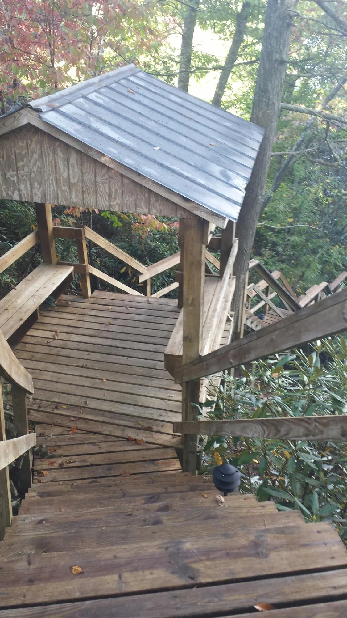 Metal roofed shelter over wooden steps on a wooded walkway — Skylight Repair & Installation work by our crew in Texas City