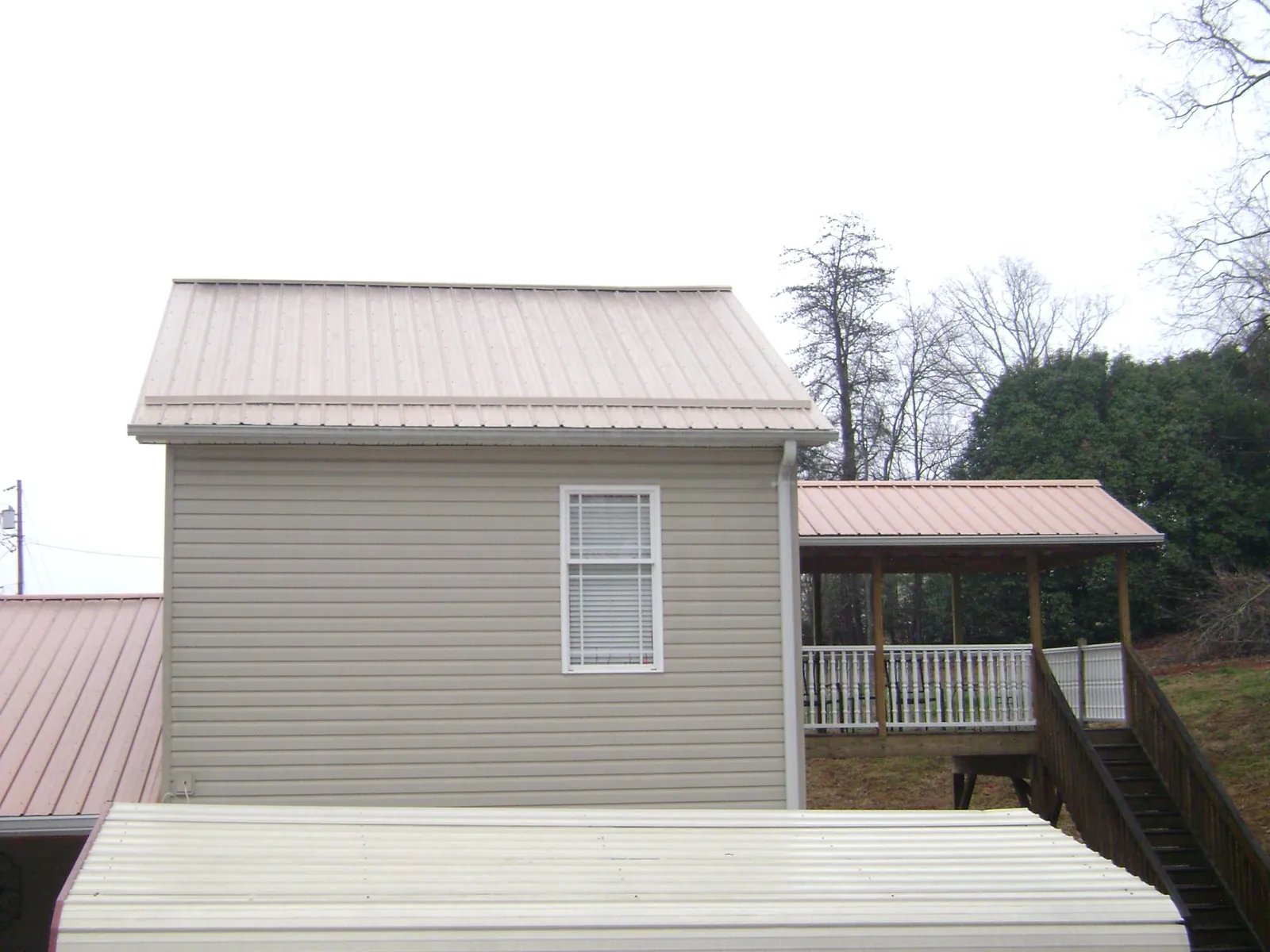 Tan metal roofs on a two story addition and attached porch, from a Roof Replacement job in Texas City