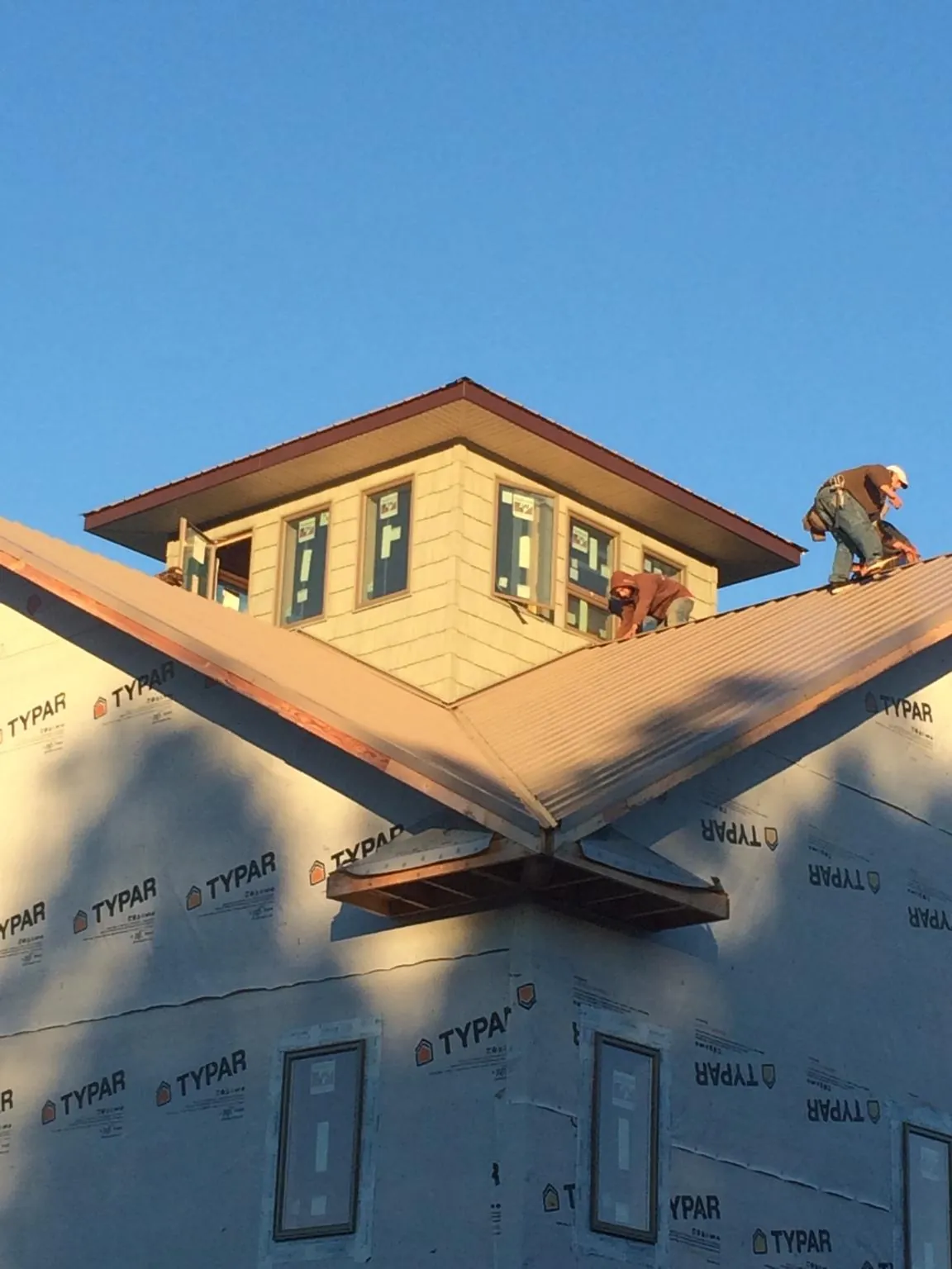 Roofers working around a rooftop cupola on a new metal roof at sunset — Roof Waterproofing in Texas City by Roofing Brothers